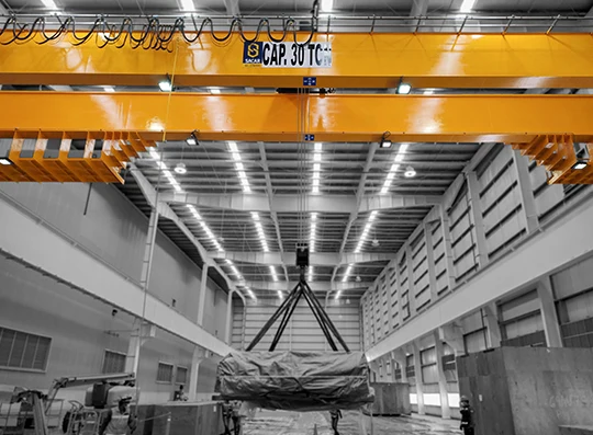Grúa viajera bipuente de 30 toneladas izando una carga en nave industrial